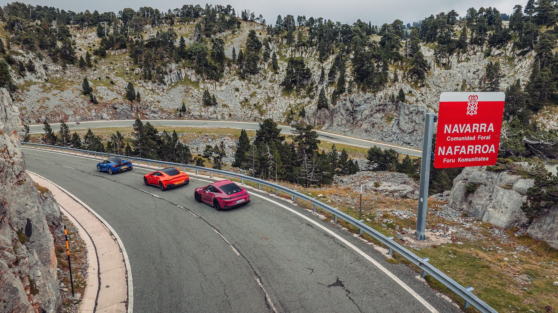 McLaren 750S blauw Aston Martin V8 Vantage oranje Porsche 911 S/T roze zijkant achter schuin hoog openbare weg bord