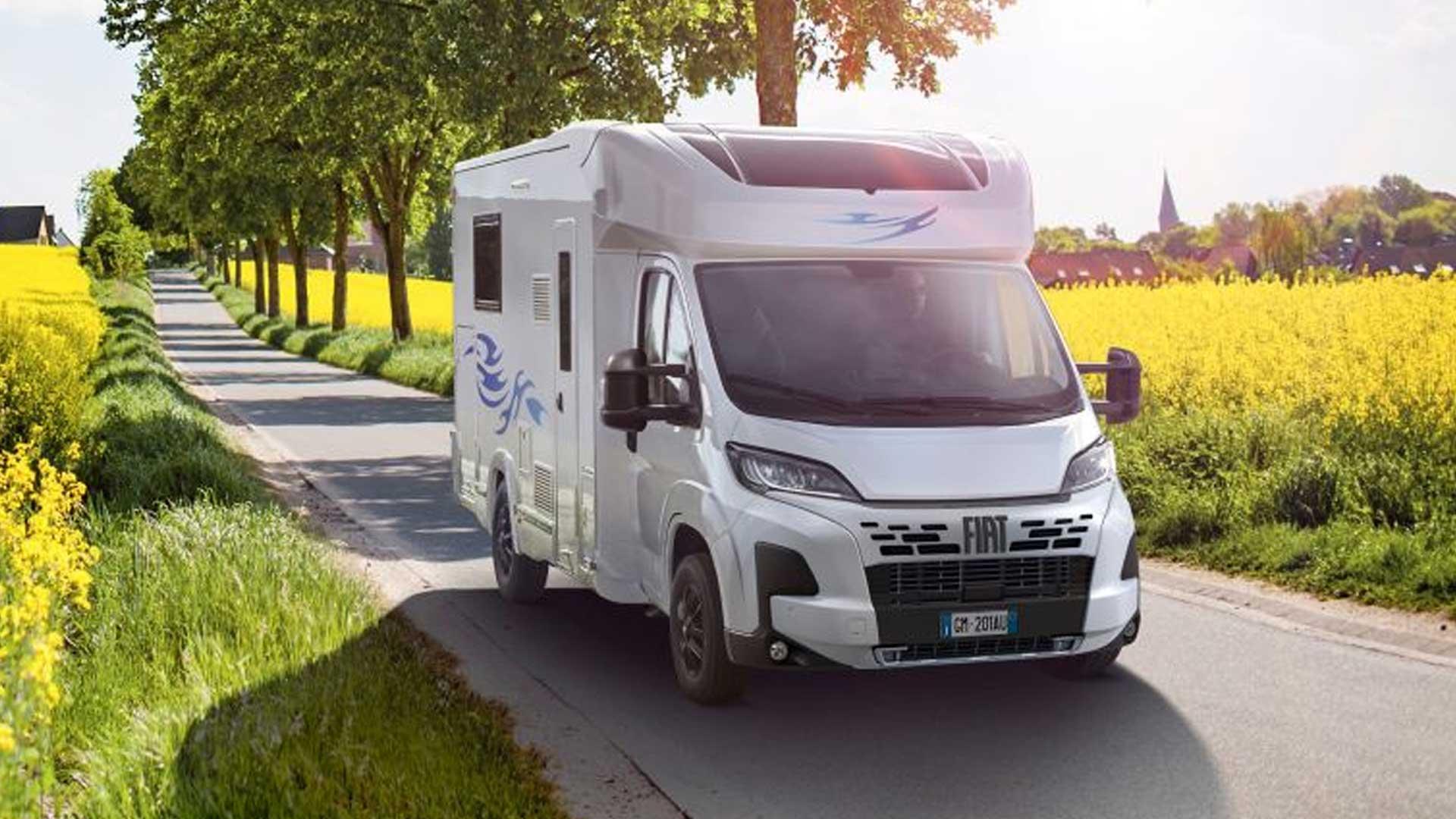 Fiat Ducato camper voorzijde bloemenweide zonlicht weg bomen