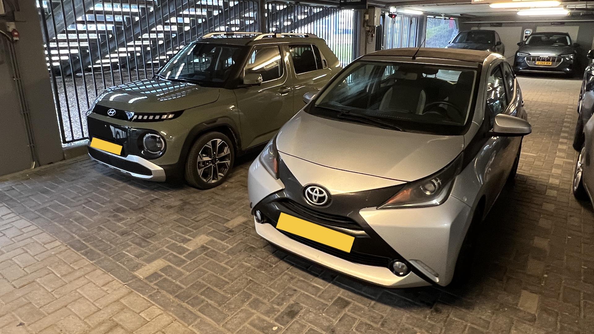 Hyundai Inster (groen) & Toyota Aygo (grijs) zijkant links in parkeergarage