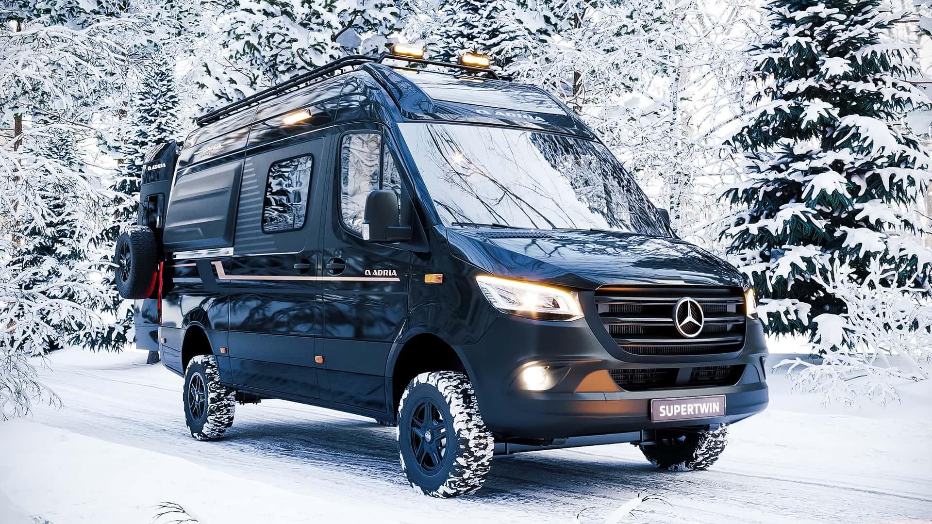 Adria Supertwin 4x4 (2024) zwart zijkant rechts schuin in de sneeuw lampen aan