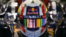 Een formule 1 auto met Max Verstappen erin met een helm op van Red Bull