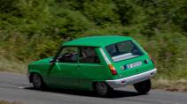 Renault 5 elektrisch rijdend op een weg schuin achter overhellend