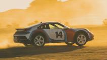 Porsche 911 Dakar met Martini-kleurstelling rijdend in de woestijn zijkant