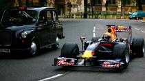 Red Bull F1-auto rijdend naast een Londense zwarte taxi