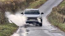 Toyota bZ4x Premium rijdend voorkant door plas water (regen)
