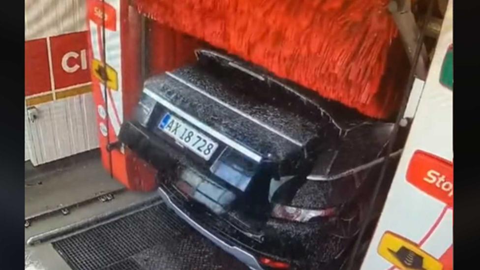 Wasborstel trekt kofferklep van auto in carwash