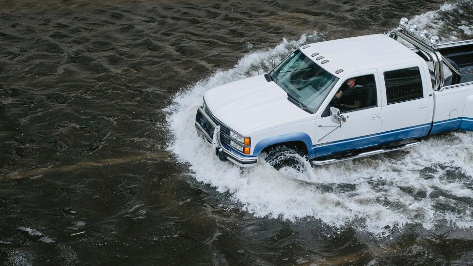 Man gebruikt pick-up om gat in dijk te dichten bij overstroming