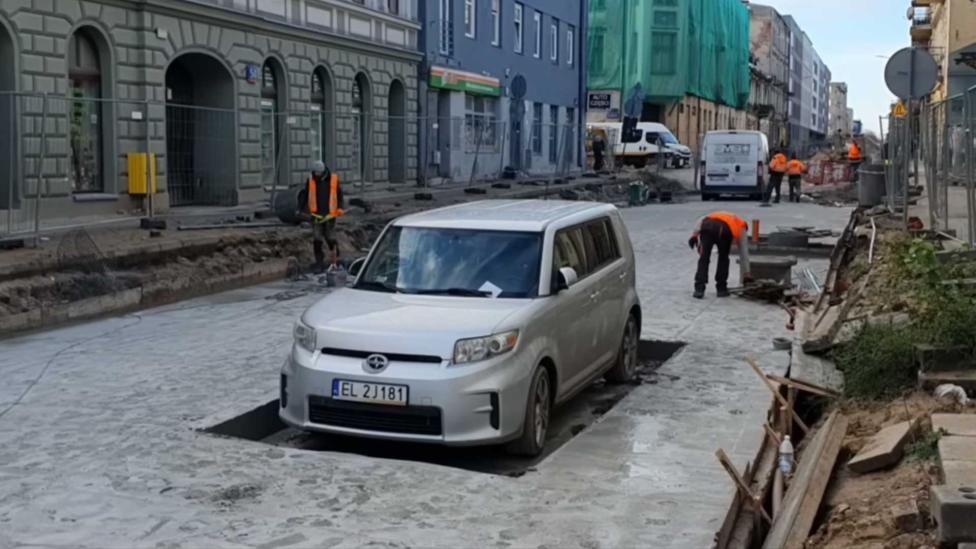 Poolse stratenmakers werken om geparkeerde auto heen